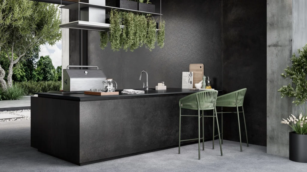Modern outdoor kitchen with black island, hanging plants, green bar stools, and surrounding greenery.