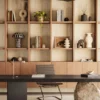 Modern desk with artistic décor, bookshelf, plants, and minimalist chair in a stylish room.