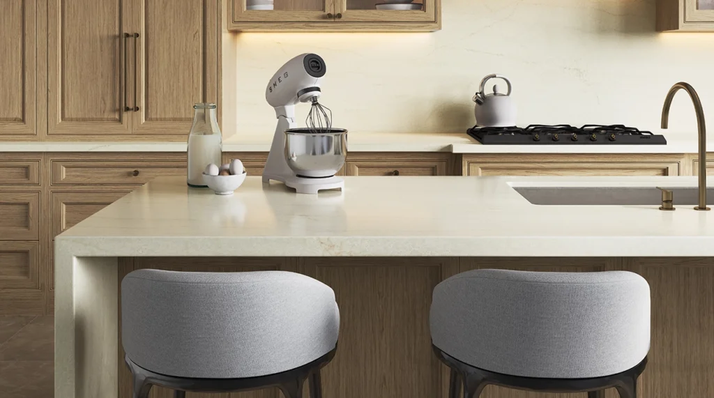 Modern kitchen island with mixer, milk, eggs, two cushioned stools, stovetop, and faucet.